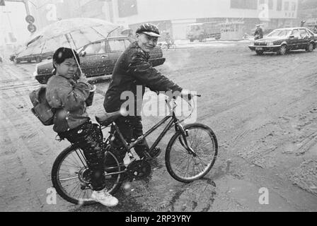 (181020) -- PÉKIN, 20 octobre 2018 () -- une photo prise en 1994 montre un homme transportant un enfant à l'école en vélo dans la neige à Qiqihar, dans la province du Heilongjiang, au nord-est de la Chine. Si vous veniez à Pékin, capitale de la Chine, il y a 40 ans, vous avez probablement été frappé par la mer des vélos dans les rues, un phénomène unique qui a valu à la Chine le titre de royaume des vélos. À cette époque, les Chinois ordinaires ne pouvaient pas se permettre de voitures et peu de gens pouvaient voyager par avion, sans parler des voyages fréquents sur de longues distances. Les trains, le moyen de transport le plus courant à l'époque, étaient toujours bourrés dans les compartiments étouffants. Banque D'Images