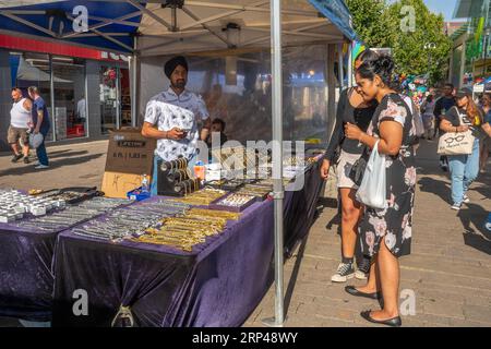 Marché de grande rue en plein air dans le centre-ville de Staines-upon-Thames, Surrey, Angleterre, Royaume-Uni. Stand de marché avec commerçant sikh indien vendant des chaînes d'or de bijoux Banque D'Images