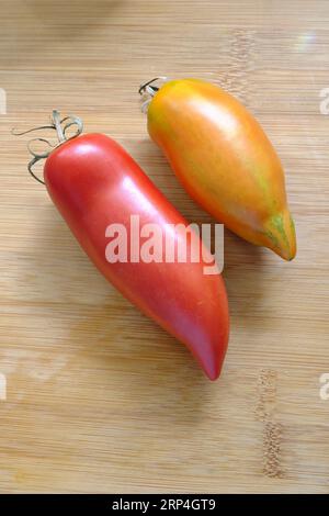 Paire de tomates Witch Nose long sur planche à découper en bois Banque D'Images