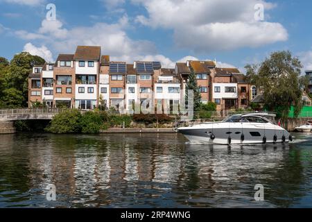 Lancement d'un moteur sur la Tamise en passant devant des propriétés riveraines coûteuses à Staines-upon-Thames, Surrey, Angleterre, Royaume-Uni Banque D'Images