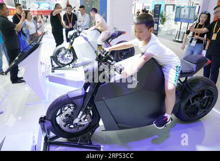 Pékin, Chine. 3 septembre 2023. Un enfant essaie une moto électrique lors de la Foire internationale chinoise du commerce des services (CIFTIS) 2023 au parc Shougang à Beijing, capitale de la Chine, le 3 septembre 2023. Le CIFTIS 2023, qui a pour thème « l'ouverture mène au développement, la coopération offre l'avenir », se tient à Beijing du 2 au 6 septembre et propose plus de 200 événements variés, y compris des forums, des négociations et des sommets. Au cours de l'événement, les technologies de pointe ont attiré les yeux des visiteurs. Crédit : Zhang Chenlin/Xinhua/Alamy Live News Banque D'Images