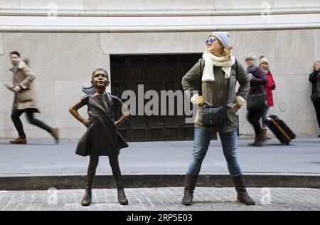 (181210) -- NEW YORK, 10 décembre 2018 -- Une femme pose pour des photos avec Fearless Girl devant la Bourse de New York, aux États-Unis, le 10 décembre 2018. Fearless Girl, une célèbre statue en bronze située dans le quartier financier de New York, a été dévoilée lundi matin dans sa nouvelle maison devant la Bourse de New York (NYSE). Fearless Girl a d'abord été installée face à face avec l'emblématique statue de Charging Bull au Bowling Green Park dans le Lower Manhattan, à quelques pâtés de maisons de son emplacement actuel, à la veille de la Journée internationale de la femme en mars 2017 en tant que temporaire Banque D'Images