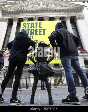 (181210) -- NEW YORK, 10 décembre 2018 -- des gens posent pour des photos avec Fearless Girl devant la Bourse de New York, aux États-Unis, le 10 décembre 2018. Fearless Girl, une célèbre statue en bronze située dans le quartier financier de New York, a été dévoilée lundi matin dans sa nouvelle maison devant la Bourse de New York (NYSE). Fearless Girl a d'abord été installée face à face avec l'emblématique statue de Charging Bull au Bowling Green Park dans le Lower Manhattan, à quelques pâtés de maisons de son emplacement actuel, à la veille de la Journée internationale de la femme en mars 2017, à titre temporaire Banque D'Images