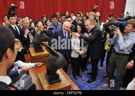 (181212) -- PÉKIN, 12 décembre 2018 (Xinhua) -- une photo prise le 28 juin 2013 montre des gens regardant deux sculptures de têtes d'animaux en bronze pillées par des envahisseurs occidentaux il y a un siècle et demi lors d'une cérémonie de remise des têtes à Pékin, capitale de la Chine. Les têtes d'un rat et d'un lapin, parties d'une horloge fontaine qui se trouvait auparavant à l'ancien Palais d'été, ou Yuanmingyuan en chinois, ont été données le 26 avril 2013 par la famille Pinault. Un navire chinois en bronze pillé à Yuanmingyuan, ou l'ancien palais d'été, est récemment retourné en Chine et est entré dans les collections de la Natio Banque D'Images