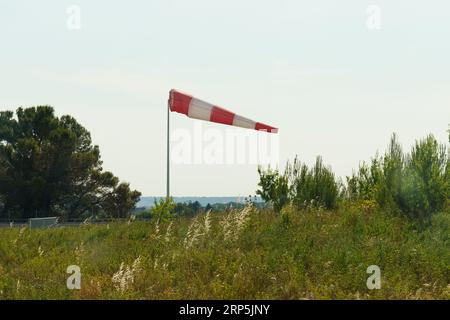 Un cône de vent rouge et blanc indiquant la direction et la force du vent. Vent fort, cône en position horizontale. Banque D'Images