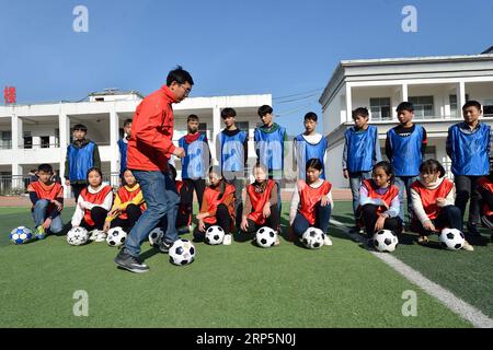 (181219) -- XIANGYANG, 19 déc. 2018 (Xinhua) -- Zheng Yu, instructeur de football, fait une démonstration de football à l'école centrale de Xiema Town, dans le canton de Xiema, dans le comté de Baokang, province du Hubei en Chine centrale, 18 déc. 2018. Xiema Town Central School, un internat rural situé dans une région montagneuse reculée de la province du Hubei, est la première école pilote de football à Baokang. L'école a construit un terrain de football en 2015, et a ajouté le football à son programme, offrant aux étudiants un accès à plus de chances de jouer au football, ainsi qu'aider les jeunes footballeurs à poursuivre leurs rêves. (Xinhua/Yang Ta Banque D'Images