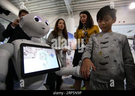 (181219) -- ATHÈNES, 19 décembre 2018 -- Un garçon interagit avec Pepper le robot, une assistance numérique spéciale montrant l'application AIA - Toorbee WeChat Miniapp, à l'aéroport international d'Athènes à Athènes, Grèce, le 19 décembre 2018. Athens International Airport a présenté mercredi ici une application pour les appareils mobiles spécialement conçus pour les voyageurs chinois, visant à faciliter davantage leur séjour à l'aéroport et dans la capitale grecque. GRÈCE-ATHÈNES-AÉROPORT-MOBILE APP-VOYAGEURS CHINOIS MARIOSXLOLOS PUBLICATIONXNOTXINXCHN Banque D'Images