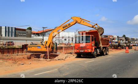 lauro de freitas, bahia, brésil - 30 août 2023 : un tracteur pelleteuse charge un camion à benne basculante avec de la terre provenant d'une zone de construction. Banque D'Images