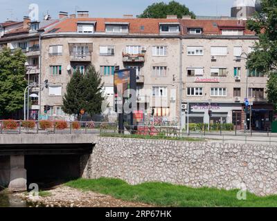 Appartement de plusieurs étages avec trous de balles et magasins au rez-de-chaussée près de la rivière Miljacka à Sarajevo, Bosnie-Herzégovine, 03 septembre 2023 Banque D'Images