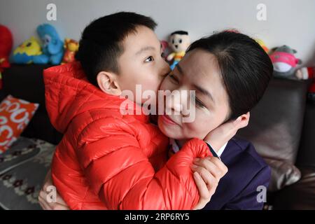 (190119) -- NANJING, 19 janv. 2019 (Xinhua) -- Zhuangzhuang embrasse sa mère Xue Feng qui est sur le point de travailler à Xuzhou, dans la province du Jiangsu de l'est de la Chine, le 18 janvier 2019. Xue Feng est un conducteur de train de la China Railway Shanghai Group Co., Ltd, dont le mari est un policier. En raison de leur travail, ils ne peuvent pas accompagner leur fils zhuangzhuang tout le temps. Chaque fois que Xue Feng doit quitter la maison pour le travail pendant quelques jours, elle écrira une note d'excuse à zhuangzhuang pour exprimer ses regrets. Et chaque fois que zhuangzhuang reçoit une note d'excuse de sa mère, il la mettra dans sa boîte au Trésor. Banque D'Images