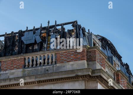 les dommages causés par le feu à l'appartement du dernier étage vidé par le feu avant d'être éteint et noirci restent sur le bâtiment. Banque D'Images