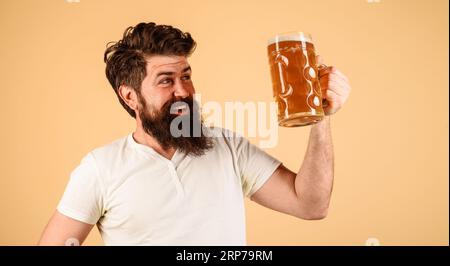 Dégustez de la bière pression. Homme souriant dans des vêtements décontractés avec un verre de délicieuse bière artisanale au café pub. Alcool. Bière en Allemagne. Célébration oktoberfest Banque D'Images