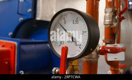 La jauge avec une flèche et des chiffres indique la pression de l'eau dans les tuyaux de la chaufferie Banque D'Images