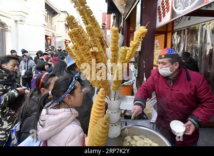 (190208) -- PÉKIN, 8 février 2019 (Xinhua) -- les touristes goûtent des collations traditionnelles dans la rue Qianmen à Pékin, capitale de la Chine, 8 février 2019. Les touristes ont visité la rue Qianmen pour profiter du paysage et des délices ici pendant les vacances de la fête du printemps. (Xinhua/Li Xin) CHINE-PÉKIN-TOURISME (CN) PUBLICATIONxNOTxINxCHN Banque D'Images