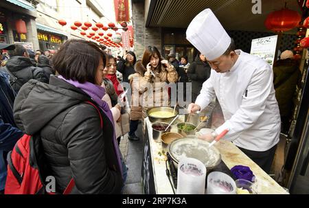 (190208) -- PÉKIN, 8 février 2019 (Xinhua) -- les touristes goûtent des collations traditionnelles dans la rue Qianmen à Pékin, capitale de la Chine, 8 février 2019. Les touristes ont visité la rue Qianmen pour profiter du paysage et des délices ici pendant les vacances de la fête du printemps. (Xinhua/Li Xin) CHINE-PÉKIN-TOURISME (CN) PUBLICATIONxNOTxINxCHN Banque D'Images