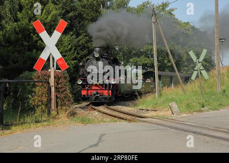 Train à vapeur Fichtelbergbahn au-dessus du passage à niveau sans porte avec St. La croix d'Andrew à la gare, attraction touristique, fumée, voie ferrée, vapeur Banque D'Images