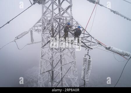 (190223) -- WUHAN, 23 février 2019 -- une photo aérienne prise le 12 février 2019 montre un travailleur d'urgence Dong Jinbing (L) inspectant le fil haute tension avec son collègue Wang Wensheng sur la tour de transmission d'énergie dans la région montagneuse de Wuhan, capitale de la province du Hubei en Chine centrale. Une équipe d'électriciens a été envoyée pour réparer un fil haute tension qui a été cassé en raison de l'accumulation d'une épaisse couche de glace. Après une journée de travail sur la tour de transmission de plus de 40 mètres de puissance dans de mauvaises conditions météorologiques, l'équipe a réussi à réparer le système électrique défaillant qui a réduit la vitesse des trains causant le dela Banque D'Images