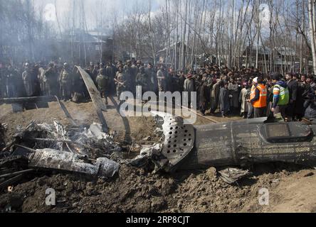 (190227) -- SRINAGAR, 27 février 2019 -- des gens et l'armée indienne se rassemblent près de l'épave d'un avion indien après qu'il s'est écrasé dans le village Garend Kalan de Budgam, à environ 34 km au sud de la ville de Srinagar, la capitale estivale du Cachemire contrôlé par l'Inde, le 27 février 2019. Un pilote et un copilote de l'Indian Air Force (IAF) ont été tués après qu'un avion mi-17 s'est écrasé mercredi dans le Cachemire contrôlé par l'Inde, ont déclaré des responsables indiens. Pendant ce temps, l'armée pakistanaise a déclaré mercredi que l'armée de l'air pakistanaise a abattu deux avions de chasse indiens à l'intérieur de l'espace aérien pakistanais et que les troupes terrestres ont arrêté un pilote du jet détruit, Banque D'Images