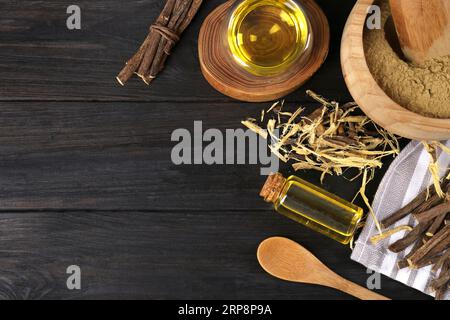 Bâtonnets séchés de racines de réglisse, copeaux et huile essentielle sur table en bois noir, pose à plat. Espace pour le texte Banque D'Images