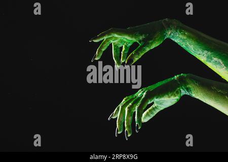 Mains de monstre vert avec des ongles noirs atteignant sur fond noir Banque D'Images