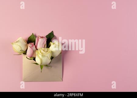 Fleurs roses blanches et roses dans l'enveloppe brune et espace de copie sur fond rose Banque D'Images