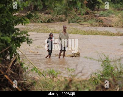 (190317) -- CHIMANIMANI (ZIMBABWE), 17 mars 2019 -- des gens marchent dans une rivière inondée à Chimanimani, province de Manicaland, Zimbabwe, 17 mars 2019. Au moins 31 personnes ont été confirmées mortes tandis que des dizaines d'autres sont toujours portées disparues alors que le cyclone tropical Idai fait des ravages dans le sud-est du Zimbabwe, a déclaré le gouvernement samedi soir. ZIMBABWE-CHIMANIMANI-CYCLONE IDAI ShaunxJusa PUBLICATIONxNOTxINxCHN Banque D'Images