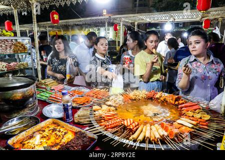 (190318) -- PÉKIN, 18 mars 2019 (Xinhua) -- les résidents goûtent des collations à un marché nocturne dans la vieille ville de Kashgar, dans la région autonome ouïgoure du Xinjiang du nord-ouest de la Chine, le 6 août 2018. L industrie chinoise des aliments et des boissons (F&B) a affiché un chiffre d affaires record de 4,27 billions de yuans (636 milliards de dollars américains) en 2018, a déclaré dimanche la China cuisine Association. Le chiffre d'affaires de l'industrie de la restauration a représenté 11,2 pour cent du volume total des ventes au détail l'an dernier, en hausse de 0,4 points de pourcentage par rapport à 2017, a déclaré Jiang Junxian, président de l'association. L'industrie de la restauration a également contribué pour 20,9 pour cent à la consommation Banque D'Images