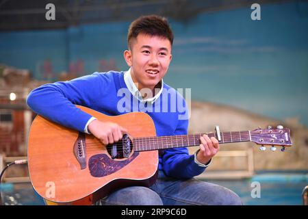 (190402) -- QINGDAO, 2 avril 2019 (Xinhua) -- Zheng Senyou joue de la guitare pour les habitants de Qingdao, dans la province du Shandong de l'est de la Chine, le 1 avril 2019. Zheng Senyou, un adolescent de 16 ans, a reçu un diagnostic d’autisme à l’âge de quatre ans. Enfant autiste, il souffre de troubles de la socialisation et du langage. Comme le traitement médical commun a peu aidé, Zheng et sa famille ont cherché des options et ont appris à connaître DFH (Diving for Humanity), une organisation non rentable et le traitement de plongée. Après une période de neuf mois de traitement, sa déficience a été atténuée. Un jour avant le World Autism Awaren Banque D'Images