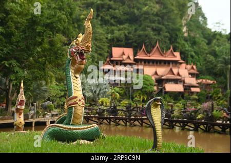 Statue de serpent devant les maisons thaïlandaises décorées au temple Tham Khao Wong. Permettre aux bouddhistes et aux touristes en général de venir visiter et voyager. Banque D'Images