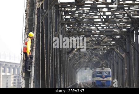 (190424) -- PÉKIN, le 24 avril 2019 -- un ouvrier attend qu'une locomotive électrique passe sur le pont ferroviaire précédent du fleuve Baishatuo Yangtze à Jiangjin, dans la municipalité de Chongqing, dans le sud-ouest de la Chine, le 23 avril 2019. Le précédent pont ferroviaire du fleuve Baishatuo Yangtze, achevé en 1959, cessera de fonctionner après avril 24. Tous les trains circuleront sur le nouveau pont ferroviaire à haubans en treillis d'acier à deux étages après ce jour-là. Le nouveau pont a 4 voies sur le pont supérieur pour les trains de voyageurs avec une vitesse nominale de 200 kilomètres par heure et 2 voies sur le pont inférieur pour les trains de marchandises avec le des Banque D'Images