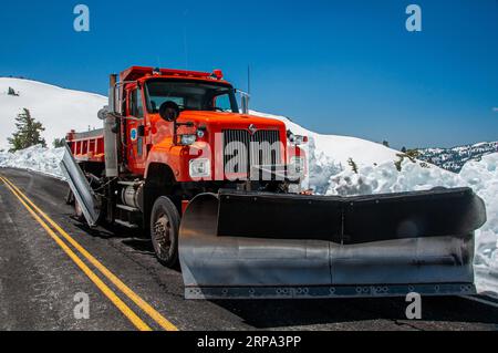 Une grande camionnette rouge est garée sur le côté d'une route enneigée, avec un vaste paysage hivernal blanc et gris en arrière-plan Banque D'Images