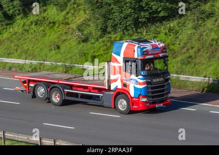 K L Holding transport Services Scania 410 camion à plateau rigide Scnaia à levage arrière avec cabine Union Jack décorée sur mesure rouge, blanche et bleue ; voyageant à grande vitesse sur l'autoroute M6 dans le Grand Manchester, Royaume-Uni Banque D'Images