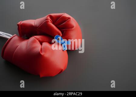 Image rapprochée de gants de boxe et ruban bleu avec espace de copie. Santé des hommes, sensibilisation au cancer, s'opposent au concept de maltraitance des enfants Banque D'Images