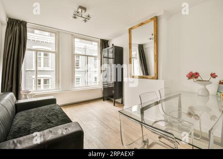 un salon avec une table en verre et canapé en cuir noir dans la chambre est très propre, mais il est tout blanc Banque D'Images