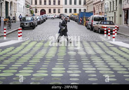 (190508) -- BERLIN, 8 mai 2019 (Xinhua) -- deux piétons traversent une rue verte dans la rue Bergmann de Kreuzberg, dans le sud de Berlin, Allemagne, le 7 mai 2019. Les points verts, qui font partie des nouveaux signaux de rue à Berlin, sont appliqués comme essai dans une partie de la rue Bergmann avec une limite de vitesse de 20 km/h, visant à inciter les véhicules à rouler à vitesse réduite. (Xinhua/Shan Yuqi) ALLEMAGNE-BERLIN-ZONE DE RUE POINTILLÉE VERTE PUBLICATIONxNOTxINxCHN Banque D'Images