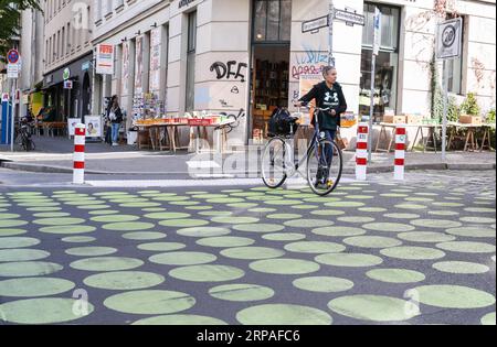 (190508) -- BERLIN, 8 mai 2019 (Xinhua) -- Un piéton à vélo traverse une rue verte dans la rue Bergmann de Kreuzberg, dans le sud de Berlin, Allemagne, le 7 mai 2019. Les points verts, qui font partie des nouveaux signaux de rue à Berlin, sont appliqués comme essai dans une partie de la rue Bergmann avec une limite de vitesse de 20 km/h, visant à inciter les véhicules à rouler à vitesse réduite. (Xinhua/Shan Yuqi) ALLEMAGNE-BERLIN-ZONE DE RUE POINTILLÉE VERTE PUBLICATIONxNOTxINxCHN Banque D'Images