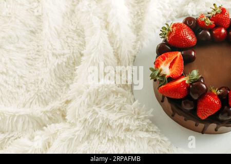 Gâteau d'anniversaire au chocolat avec fraises et cerises sur fond blanc. Vue d'en haut. Photo pour le menu ou catalogue de confiseries. Banque D'Images