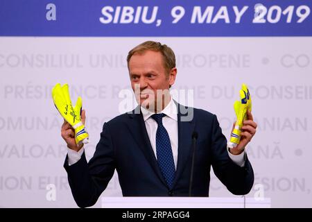 (190509) -- SIBIU (ROUMANIE), 9 mai 2019 -- le président du Conseil européen Donald Tusk fait un geste avec une paire de gants de gardien de but qu'il a reçu de Helmuth Duckadam, ancien gardien roumain de football, lors d'une conférence de presse conjointe d'un sommet informel de l'UE à Sibiu, Roumanie, le 9 mai 2019. Le président du Conseil européen, Donald Tusk, a annoncé jeudi soir qu'il convoquerait une réunion avec les dirigeants des États membres de l'Union européenne (UE) le 28 mai afin d'établir les procédures de nomination des nouveaux dirigeants de l'UE. ROUMANIE-SIBIU-UE-SOMMET INFORMEL-CONFÉRENCE DE PRESSE CRISTIANXCRISTEL PUBLICATIONXNOTXINXCHN Banque D'Images