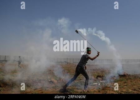 (190515) -- GAZA, 15 mai 2019 -- Un manifestant palestinien utilise une fronde pour jeter une cartouche de gaz lacrymogène tirée par les troupes israéliennes lors d'affrontements à la frontière Gaza-Israël à l'est de la bande de Gaza, le 15 mai 2019. Au moins 47 Palestiniens ont été blessés mercredi dans leurs affrontements avec des soldats israéliens, alors qu’ils célébraient le 71e anniversaire de la Nakba, ou jour de la catastrophe, le lendemain de la déclaration d’indépendance d’Israël en 1948. MIDEAST-GAZA-AFFRONTEMENTS Stringer PUBLICATIONxNOTxINxCHN Banque D'Images