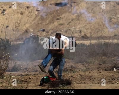 (190515) -- GAZA, le 15 mai 2019 -- Un manifestant palestinien transporte un blessé lors d'affrontements avec les troupes israéliennes à la frontière Gaza-Israël, à l'est du camp de réfugiés d'al-Bureij dans le centre de Gaza, le 15 mai 2019. Au moins 47 Palestiniens ont été blessés mercredi dans leurs affrontements avec des soldats israéliens, alors qu’ils célébraient le 71e anniversaire de la Nakba, ou jour de la catastrophe, le lendemain de la déclaration d’indépendance d’Israël en 1948. MIDEAST-GAZA-AFFRONTEMENTS YasserxQudih PUBLICATIONxNOTxINxCHN Banque D'Images