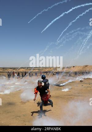 (190515) -- GAZA, 15 mai 2019 -- des Palestiniens courent pour se mettre à couvert par des bombes lacrymogènes tirées par les troupes israéliennes lors d'affrontements à la frontière Gaza-Israël, à l'est du camp de réfugiés d'al-Bureij, dans le centre de Gaza, le 15 mai 2019. Au moins 47 Palestiniens ont été blessés mercredi dans leurs affrontements avec des soldats israéliens, alors qu’ils célébraient le 71e anniversaire de la Nakba, ou jour de la catastrophe, le lendemain de la déclaration d’indépendance d’Israël en 1948. MIDEAST-GAZA-AFFRONTEMENTS YasserxQudih PUBLICATIONxNOTxINxCHN Banque D'Images