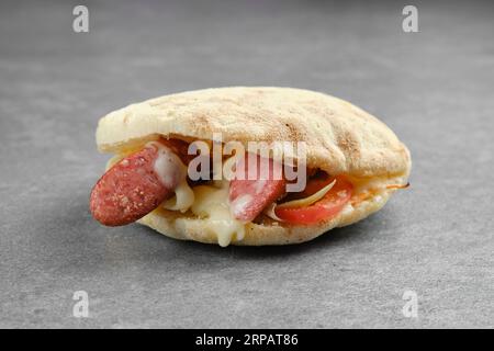 Pain pita avec saucisse fine, oignon mariné, tranches de tomate fraîches et fromage fondu Banque D'Images