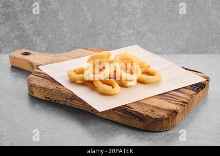 Rondelles d'oignon épicées frites sur parchemin Banque D'Images