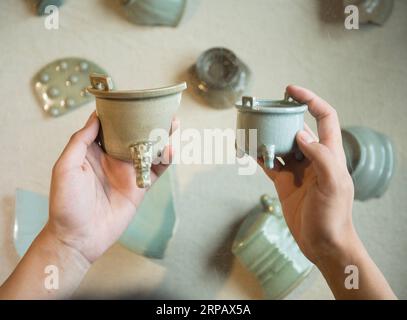 (190520) -- LONGQUAN, 20 mai 2019 (Xinhua) -- Lin Song montre une pièce de sa collection de brûleurs d'encens classiques Longquan céladon (à gauche) et la réplique correspondante faite par lui à Longquan, dans la province de Zhejiang de l'est de la Chine, le 20 mai 2019. Né en 1993, Lin Song est originaire de Longquan, qui abrite les meilleures marchandises de céladon en Chine. Il a reçu une formation professionnelle à la fois dans sa ville natale et à Jingdezhen, un autre centre important de porcelaine de Chine. Lin a également suivi d'autres artisans de céladon pendant des années avant de créer un studio chez lui en 2014, se concentrant sur la réplication du céladon ince classique Banque D'Images