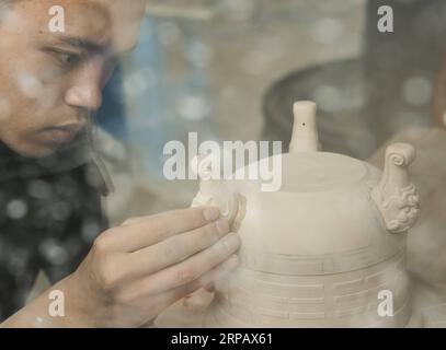 (190520) -- LONGQUAN, 20 mai 2019 (Xinhua) -- Lin Song travaille sur la base d'argile pour un brûleur d'encens céladon dans son atelier de Longquan, province du Zhejiang dans l'est de la Chine, 20 mai 2019. Né en 1993, Lin Song est originaire de Longquan, qui abrite les meilleures marchandises de céladon en Chine. Il a reçu une formation professionnelle à la fois dans sa ville natale et à Jingdezhen, un autre centre important de porcelaine de Chine. Lin avait également suivi d'autres artisans céladons pendant des années avant d'installer un studio chez lui en 2014, se concentrant sur la réplication des brûleurs d'encens céladons classiques. La collection personnelle de LIN a augmenté à plus de 40 céladons Banque D'Images