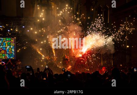 Dragon mythique dansant dans un spectacle pyrotechnique avec feu d'artifice tiré de sa tête. Les gens enregistrent avec leurs téléphones portables et un orchestre jouant M. Banque D'Images