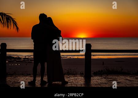 Broome, WA, Australie - Silhouette d'un couple serrant et regardant le coucher du soleil Banque D'Images