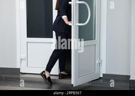 Femme en costume élégant quittant ou entrant dans l'immeuble de bureaux, closeup Banque D'Images