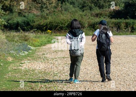 Deux femmes asiatiques, avec des sacs à dos marchant ensemble le long d'un chemin de gravier dans la campagne anglaise. Septembre 2023 Banque D'Images