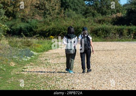 Deux femmes asiatiques, avec des sacs à dos marchant ensemble le long d'un chemin de gravier dans la campagne anglaise. Septembre 2023 Banque D'Images